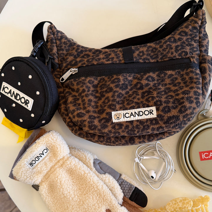 Crescent Bag in Leopard: flat lay with a Polka Dot Dingle Dangle Bag, fleece gloves and earphones