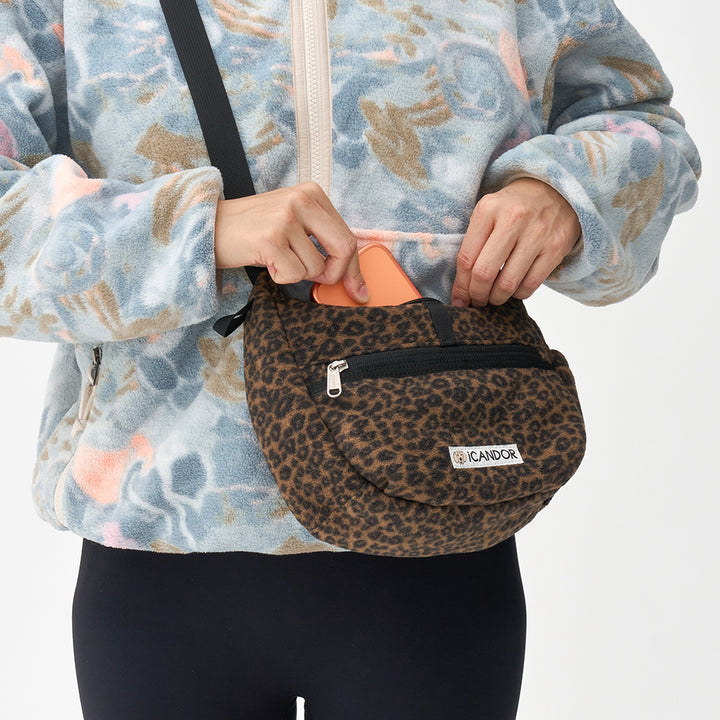 Crescent Bag in Leopard: unzipping the main compartment with a phone inside, worn crossbody